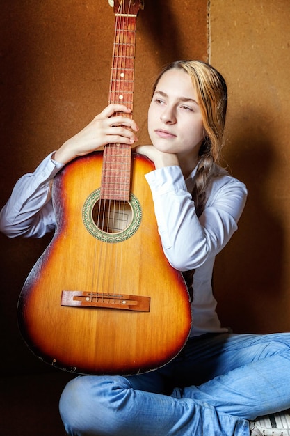 Jonge hipster vrouw zittend op de vloer en gitaar spelen thuis Tiener meisje leren om liedjes te spelen en muziek te schrijven in haar kamer Hobby levensstijl ontspannen Instrument vrijetijdsbesteding onderwijs concept