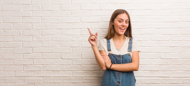 Jonge hipstervrouw die aan de kant met vinger richten