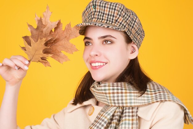 Foto jonge hipstervrouw in trendy herfstoutfit, stijlvolle muts en sjaal, schoonheidsmeisje houdt herfstverlof