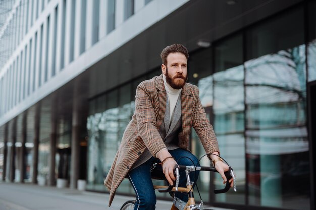 Jonge hipsterzakenman die aan het milieuvriendelijke vervoersconcept van de fiets gaat werken