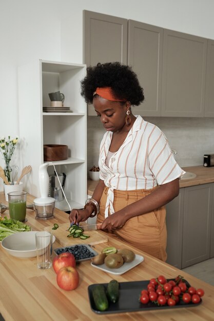 Jonge huisvrouw die groentesalade in de keuken kookt