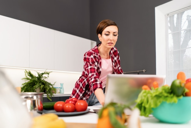 Jonge huisvrouw die online recepten zoekt