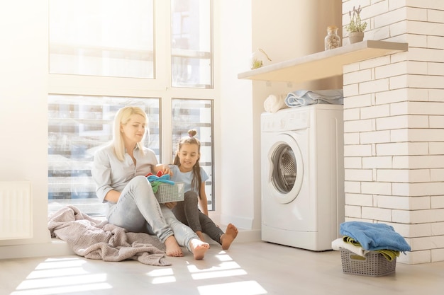 Jonge huisvrouw en klein meisje samen de was doen