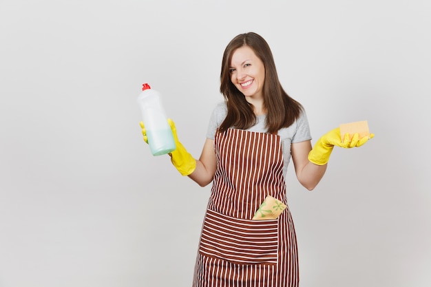 Jonge huisvrouw in gele handschoenen, gestreepte schort, poetslap in zak geïsoleerd op een witte achtergrond. vrouw met fles met schonere vloeistof voor de afwas, spons. kopieer ruimte voor advertentie.