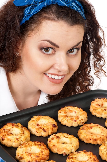 Jonge huisvrouw met een dienblad met koekjes vers uit de oven op een witte achtergrond