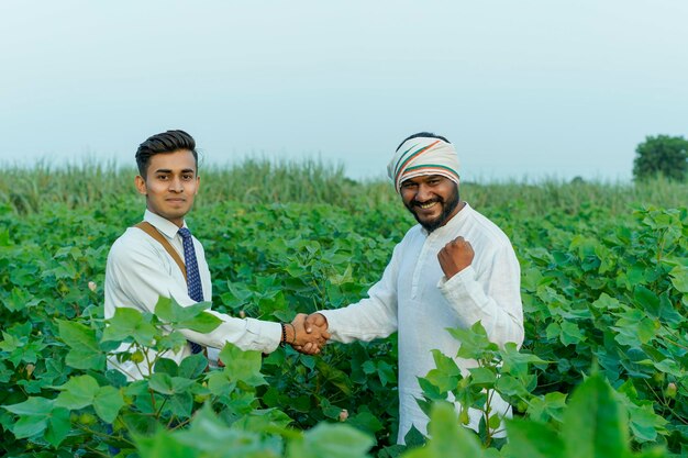 Foto jonge indiase agronoom of bankier die informatie toont aan een boer op het landbouwveld