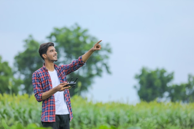 Jonge Indiase agronoom werkt of bestuurt vliegende drone op landbouwgebied