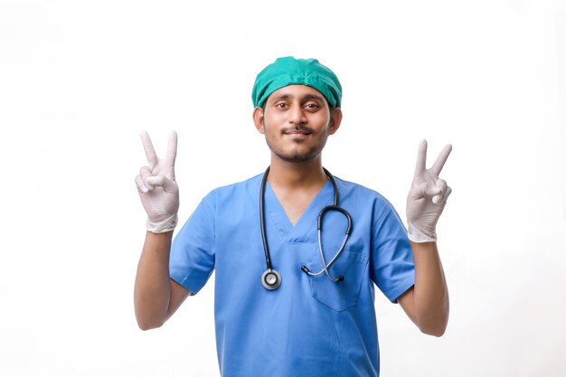 Jonge Indiase arts die overwinningsteken toont op witte achtergrond.