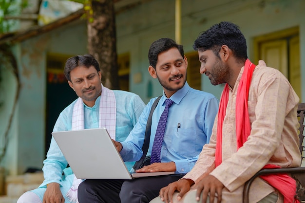 Jonge Indiase bankier of agronoom die wat detail toont aan boeren in laptop thuis
