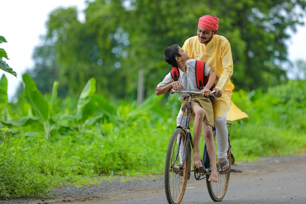 Jonge Indiase boer en zijn zoon gaan op de fiets naar school