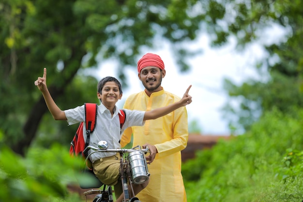 Jonge Indiase boer en zijn zoon gaan op de fiets naar school