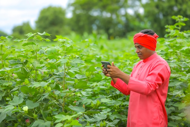 Jonge Indiase boer met behulp van mobiele telefoon op landbouwgebied