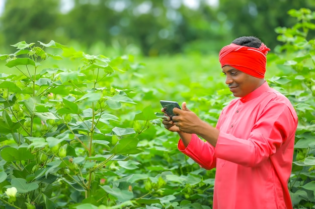 Jonge Indiase boer met behulp van mobiele telefoon op landbouwgebied