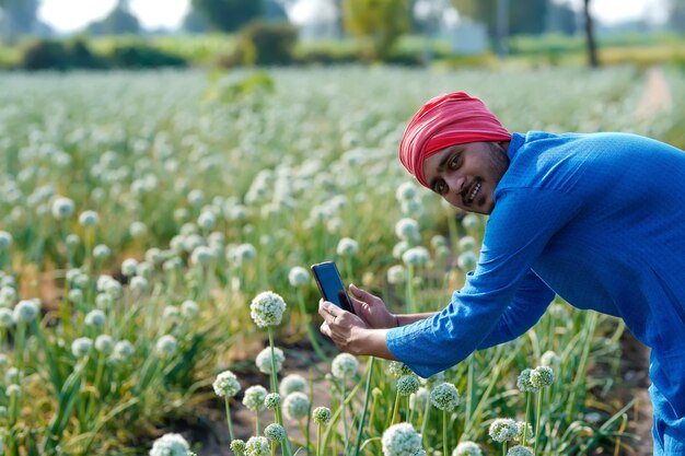 Jonge Indiase boer met behulp van smartphone op landbouwgebied
