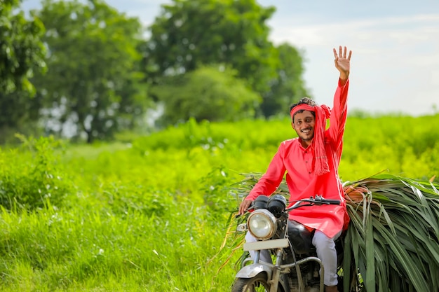 Jonge Indiase boer met veevoedsel op een motor