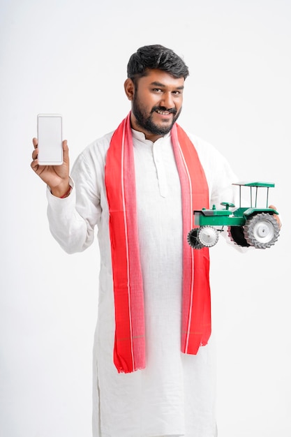 Jonge Indiase boer weergegeven: tractor speelgoed en smartphone op witte achtergrond