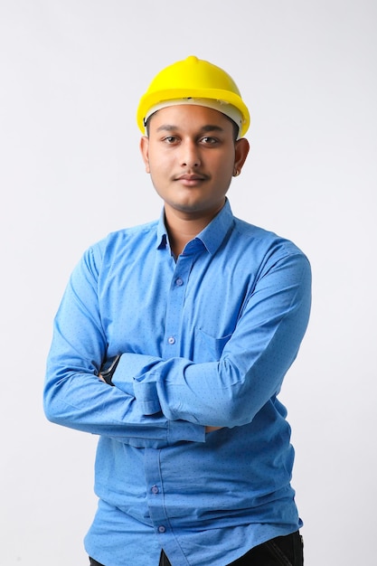 Jonge Indiase ingenieur die een gele helm draagt en een succesvol gebaar geeft.
