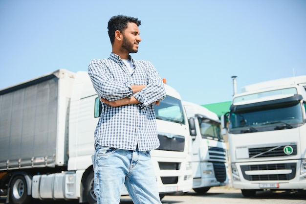 Jonge Indiase man die bij zijn vrachtwagen staat Het concept van vrachtvervoer