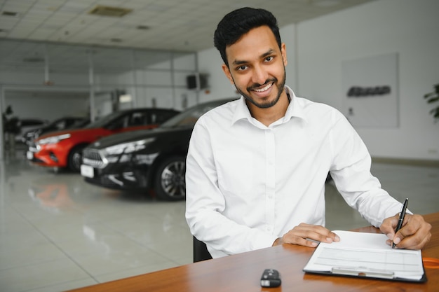 Jonge Indiase man die documenten ondertekent bij autodealer