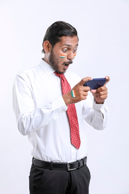 Jonge indiase man die schokkende uitdrukking geeft na het zien van een smartphone.
