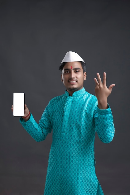 Jonge Indiase man in traditionele slijtage en weergegeven: smartphone.