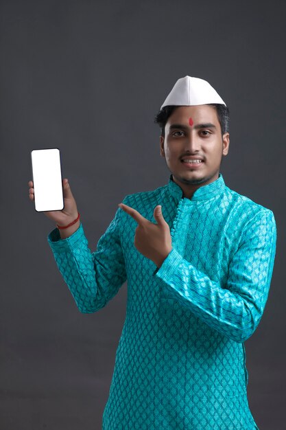 Jonge Indiase man in traditionele slijtage en weergegeven: smartphone.