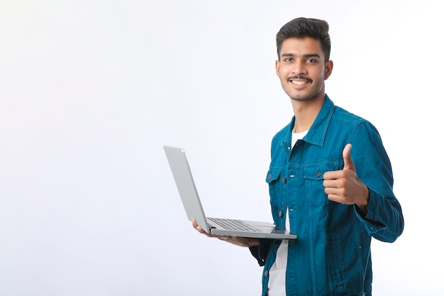 Jonge Indiase man met behulp van laptop en dreunen op een witte achtergrond.