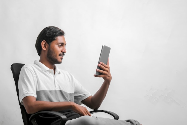Jonge Indiase man met behulp van tablet op witte achtergrond.