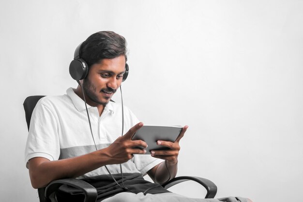 Jonge Indiase man met behulp van tablet op witte achtergrond.