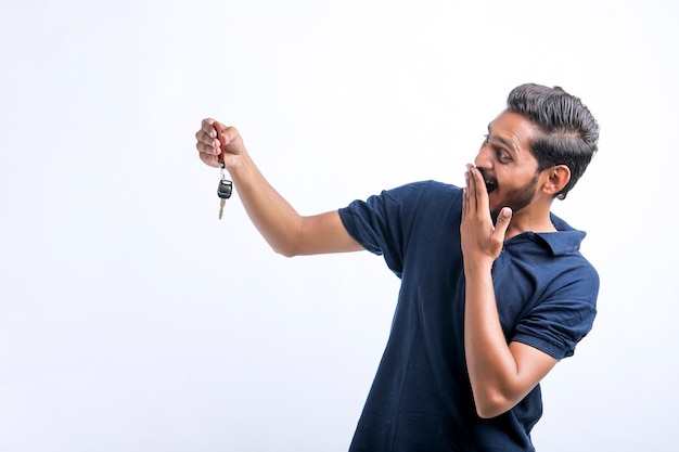 Jonge Indiase man met sleutel in de hand op witte achtergrond.