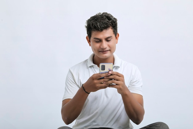 Jonge Indiase man met smartphone op witte achtergrond.