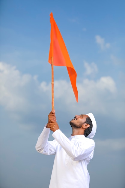 Jonge Indiase man (pelgrim) in traditionele slijtage en wuivende religieuze vlag.