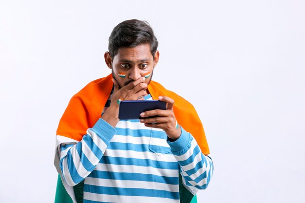 Jonge indiase man viert onafhankelijkheidsdag of dag van de republiek en gebruikt smartphone