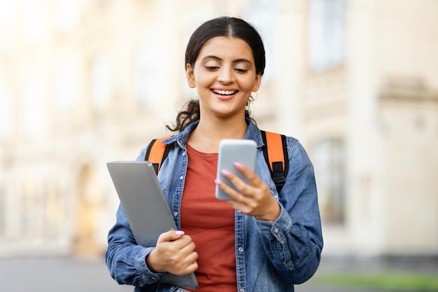 Jonge Indiase student die sms't op zijn smartphone op de campus