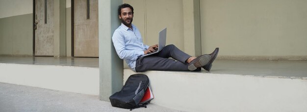 Jonge Indiase student met laptop op universiteitscampus