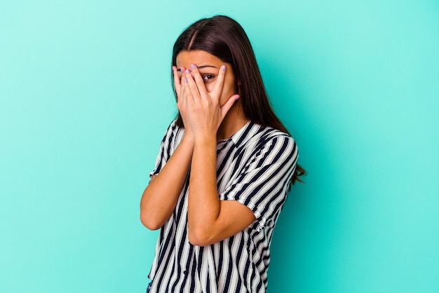 Jonge Indiase vrouw geïsoleerd op blauwe achtergrond knipperen door angstige en nerveuze vingers.