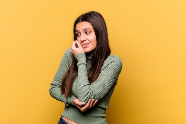 Jonge Indiase vrouw geïsoleerd op geel verward, twijfelachtig en onzeker.