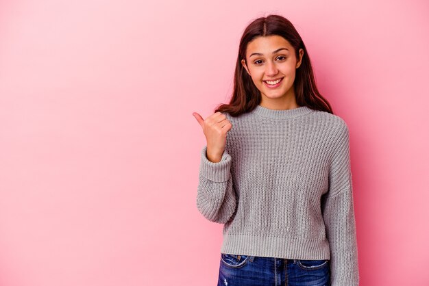 Jonge Indiase vrouw geïsoleerd op roze achtergrond geschokt wijzend met wijsvingers naar een kopieerruimte.