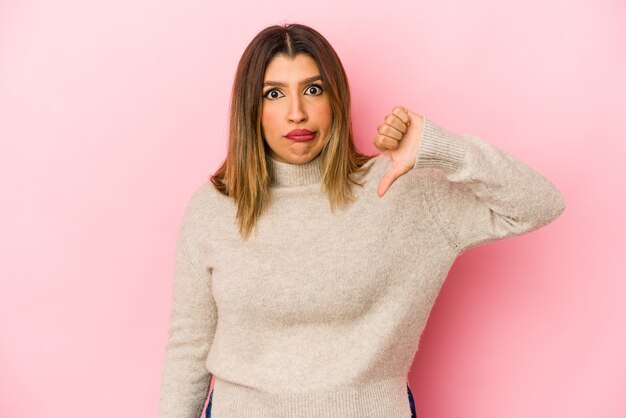 Jonge Indiase vrouw geïsoleerd op roze muur met duim omlaag, teleurstelling concept