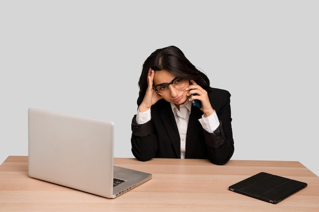 Jonge Indiase vrouw in een tafel met een laptop en tablet met behulp van een mobiele telefoon geïsoleerd