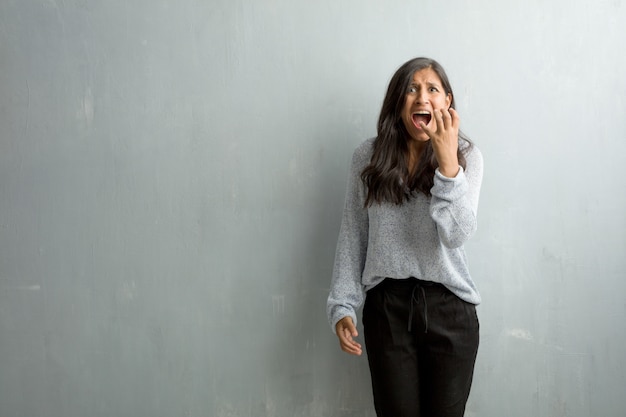 Jonge Indiase vrouw tegen een grunge muur erg bang en bang, wanhopig op zoek naar iets