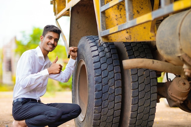 Jonge indiase zakenman met zijn vrachtauto of vrachtwagen.