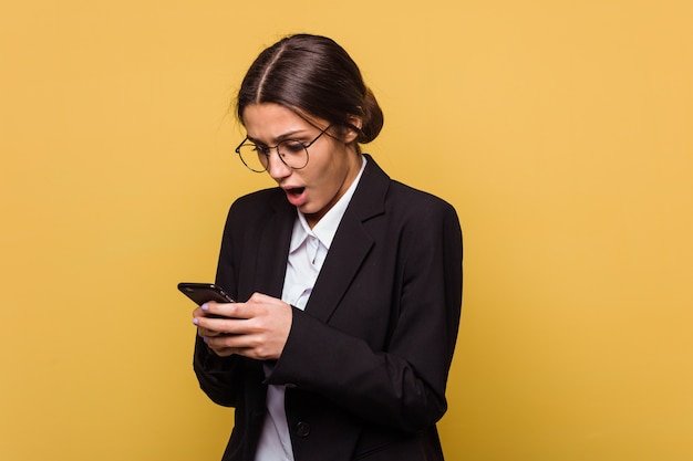 Jonge Indiase zakenvrouw praten over telefoon geïsoleerd op gele muur