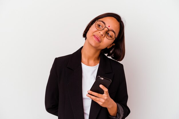 Jonge indische bedrijfsvrouw die een geïsoleerde telefoon houdt die van het bereiken van doelstellingen en doeleinden droomt