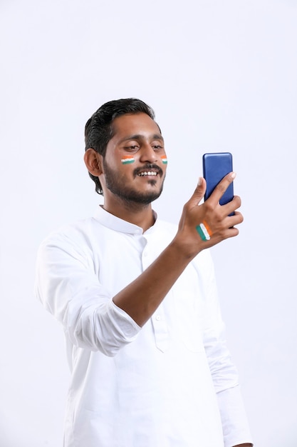 Jonge indische man viert onafhankelijkheidsdag of dag van de republiek en gebruikt smartphone.