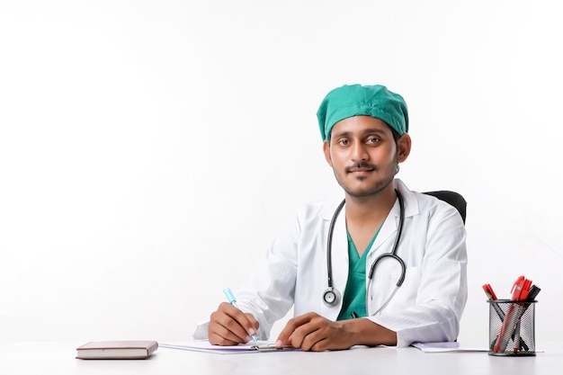 Jonge indische mannelijke arts die op blocnote bij kliniek schrijft.