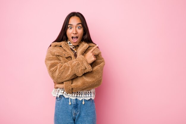 Jonge Indische vrouw die een korte schapehuidlaag draagt die aan de kant richt