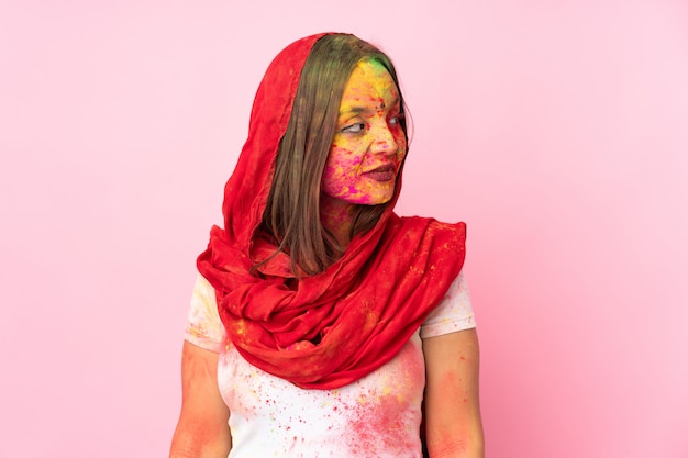 Foto jonge indische vrouw met kleurrijk holipoeder op haar gezicht op roze muur