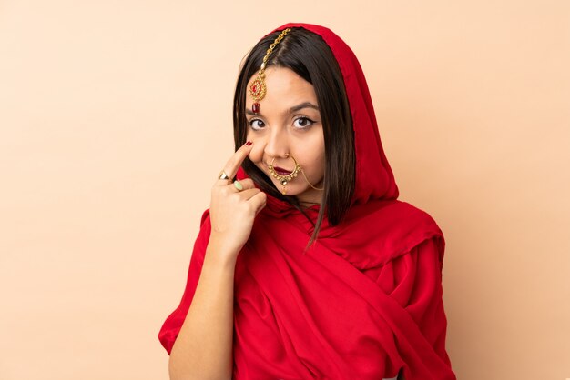 Jonge Indische vrouw op beige muur die iets toont