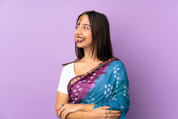 Jonge Indische vrouw op purpere gelukkig en muur die glimlachen